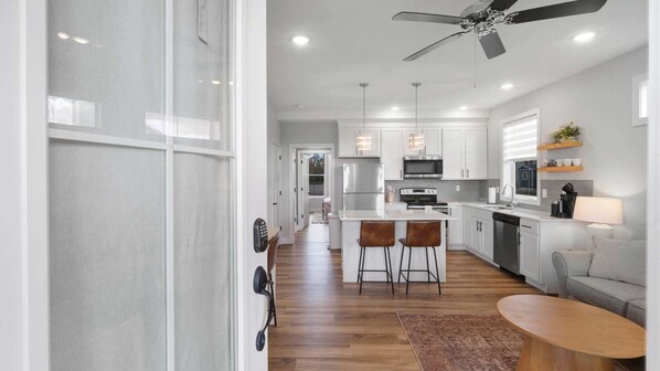A modern kitchen with white cabinets, stainless steel appliances, and a central island with bar stools.