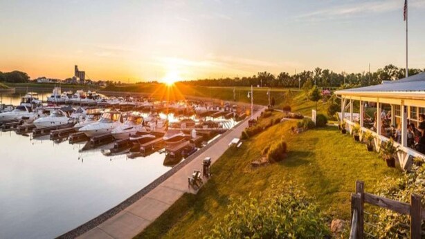 A marina with boats docked, a grassy area, and a covered structure with people. - Mansion Flat @ Navvy Town (Ottawa)