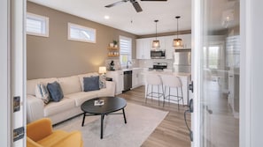 A modern kitchen with white cabinets, a stainless steel refrigerator, and a bar area.