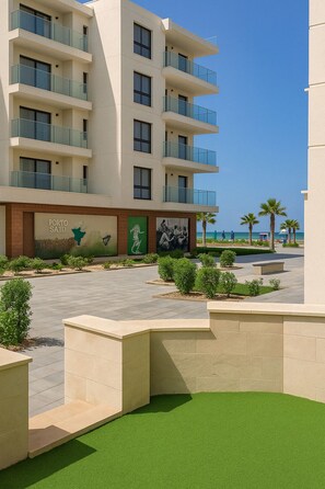 Enjoy ocean views from the balconies with glass railings, overlooking a landscaped area and the beach.