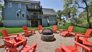 Un bâtiment à deux étages doté d’un balcon, d’un foyer extérieur et de chaises Adirondack rouges disposées autour.