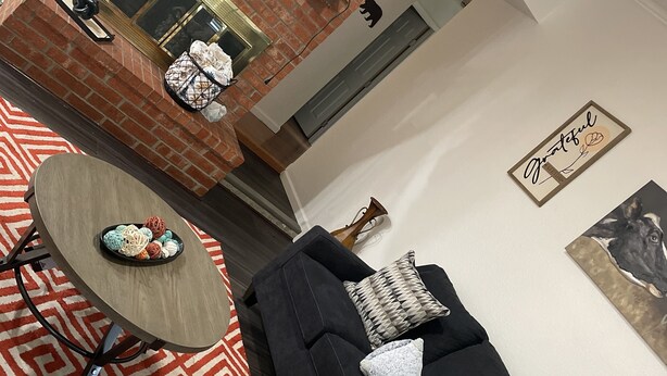 A modern living room with a black sofa, a round coffee table, and a patterned rug.