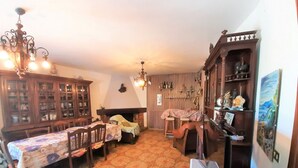 Quarto tradicional com uma mesa de jantar, cadeiras, lareira e um armário de madeira com prateleiras.