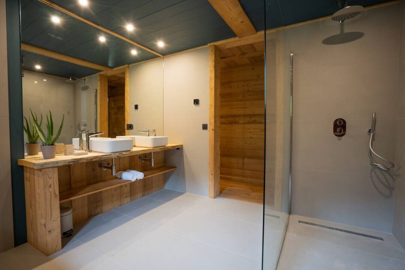 Een moderne badkamer met houten details, een douchecabine van glas en een grote spiegel.