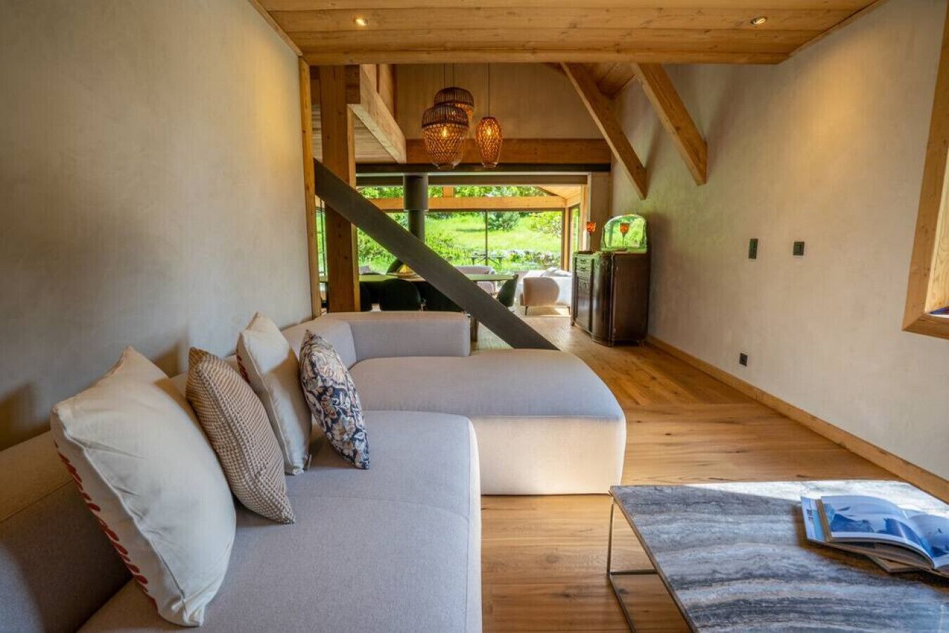 Un interior moderno con un sofá modular, vigas de madera y vistas al exterior.