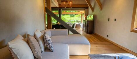 Un interior moderno con un sofá modular, vigas de madera y vistas al exterior.