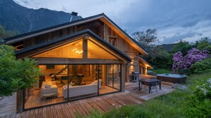 A modern wooden cabin with a glass-enclosed living area, a deck, and a hot tub.