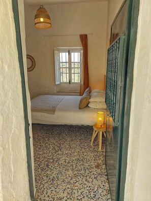 Relax in this serene bedroom with a comfortable bed, a window with curtains, and a soft candlelit ambiance.