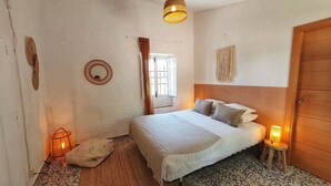 Une chambre à coucher avec un lit, des lampes de chevet, un miroir et une porte en bois.