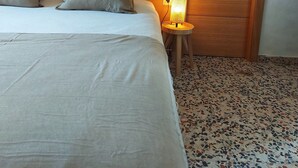 Une chambre à coucher avec un lit, des oreillers, une lampe de chevet, une armoire en bois et une décoration murale en macramé.