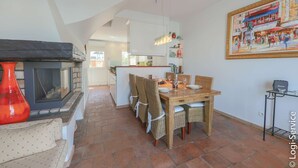 A dining area with a wooden table, wicker chairs, and a fireplace. - Air-conditioned house, close to beach 9 people  et  mooring (PORT GRIMAUD)