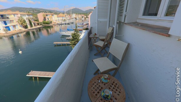 A balcony with a table and chairs overlooking a marina with boats. - Air-conditioned house, close to beach 9 people  et  mooring (PORT GRIMAUD)