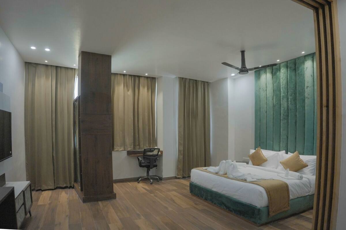 A modern hotel room with a large bed, a desk, and a ceiling fan.