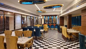 Un restaurant dont le sol est recouvert de carreaux, avec des tables rondes et des chaises jaunes et bleues.