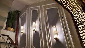 Un escalier avec une rampe, un pot de fleurs et des appliques murales.