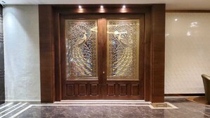 Une porte en bois à deux battants, ornée de panneaux de verre complexes, et un sol en marbre.