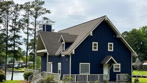 A two-story house with a dark blue exterior, a front porch, and a visible chimney. - 
Centerport GetAway, Family size cabin. Near restaurants, golf and AU football (Dadeville)