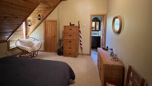 A bedroom with a sloped ceiling, a ceiling fan, a bed, a dresser, a chair, and a small table. - 
Centerport GetAway, Family size cabin. Near restaurants, golf and AU football (Dadeville)