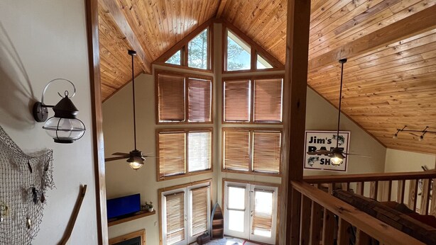 A wooden interior with a high ceiling, multiple windows, a staircase, and a sign for "Jim's Bar & Shop". - 
Centerport GetAway, Family size cabin. Near restaurants, golf and AU football (Dadeville)