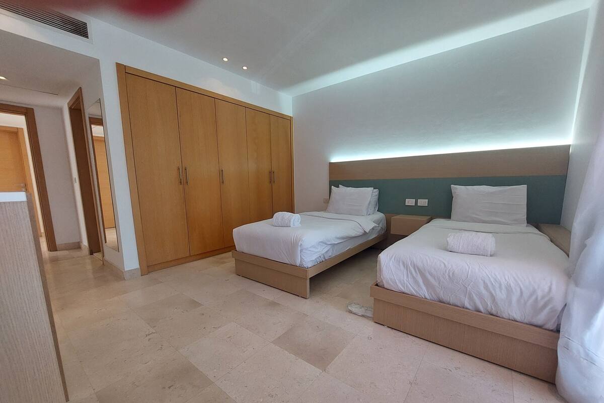 A hotel room with two beds, a wardrobe, and a bathroom.