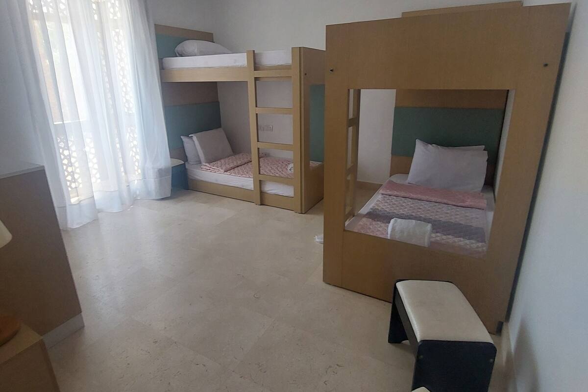 A dormitory room with bunk beds, a small desk, and a chair.