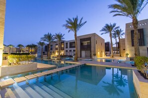 Un hôtel moderne doté d’une piscine, de palmiers et d’une architecture contemporaine.