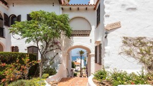 A white building with arches and a tiled pathway leading to a view of the sea. - Sunset Tirant, Your seaside retreat (Platges de Fornells)