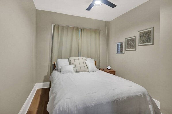 A bedroom with a bed, a nightstand, a ceiling fan, and two framed pictures on the wall. - The Kaya Top Suite-Dwntwn West 8 (Indianapolis)