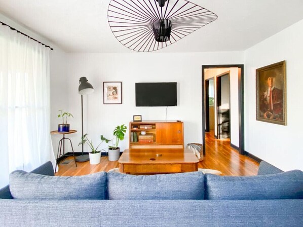Una sala de estar moderna con un sofá azul, una mesa de centro de madera y un ventilador de techo original.