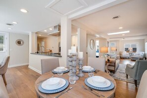 Un comedor con una mesa redonda preparada para cuatro personas, un espejo y vista a la cocina.