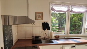 Una cocina con encimera de madera, un lavamanos, un lavavajillas Bosch y una ventana con vistas a zonas verdes.