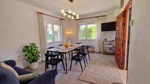 A dining area with a table set for four, a sofa, a potted plant, and a TV on a wooden cabinet. - La Gallega - Denia, Costa Blanca (Denia)