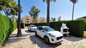 A paved driveway with a white car parked on the right, leading to a building with balconies. - La Gallega - Denia, Costa Blanca (Denia)