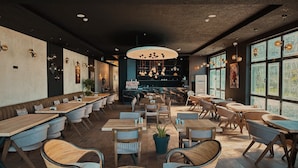 Un restaurante moderno con mesas largas compartidas, cabinas individuales y una zona de bar central.