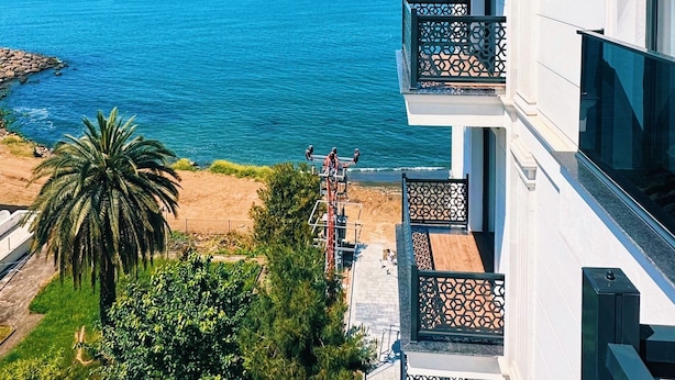 Un hotel de varios pisos con balcones que dan a una playa y al mar.