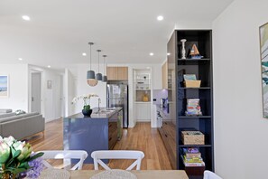 A modern kitchen with a central island, built-in shelves, and a dining area with a table and chairs.