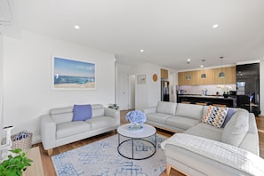 A modern living room with two sofas, a coffee table, and a kitchen in the background.
