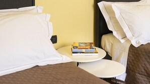 Una habitación de hotel con una cama, una mesita de noche con libros y una pequeña mesa redonda.