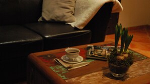 Un canapé en cuir foncé avec un coussin blanc, une petite table sur laquelle se trouve une tasse de café, un magazine et une plante en pot.