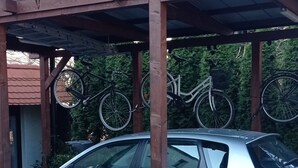 Une voiture était garée sous une pergola en bois, et des vélos étaient suspendus au-dessus.