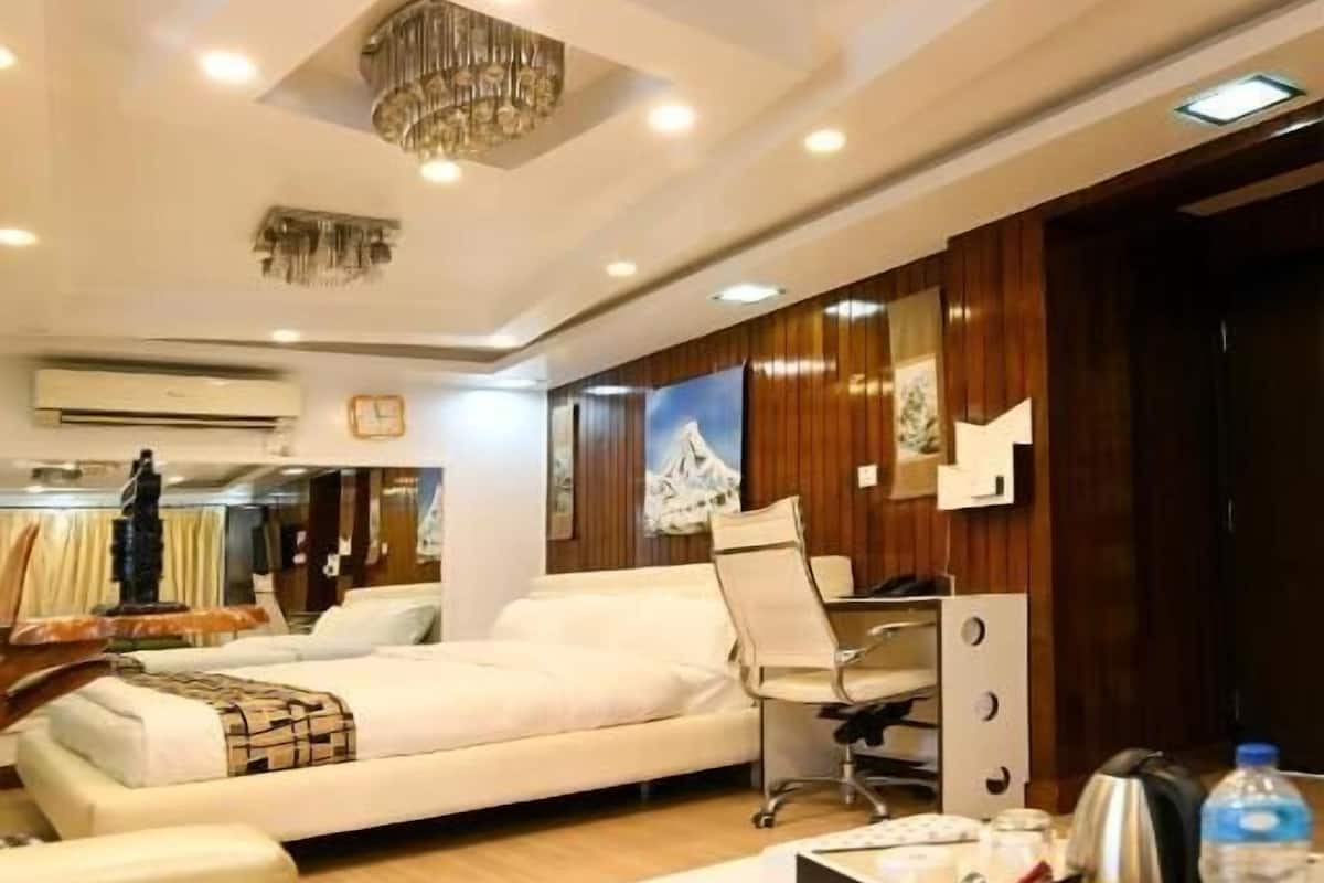 A modern hotel room with a large bed, a desk with a chair, and a chandelier.