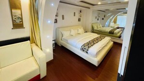 Un dormitorio moderno con una cama grande, un sofá y un espejo que refleja la habitación.