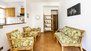 Een woonkamer met een bank, twee fauteuils, een salontafel en een boekenkast.