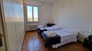 A room with two beds, a radiator, a window, and a wooden floor. - Nazionale 37 in Firenze (Florence)