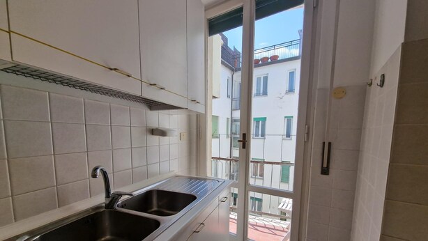 A kitchen with two sinks, white cabinets, and a view of a balcony with buildings. - Nazionale 37 in Firenze (Florence)