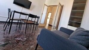 A living room with a sofa, a TV mounted on the wall, a dining table with chairs, and a door leading to another room. - Nazionale 37 in Firenze (Florence)