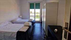 A hotel room with two beds, a desk, a wardrobe, and a window with a view of buildings. - Nazionale 37 in Firenze (Florence)