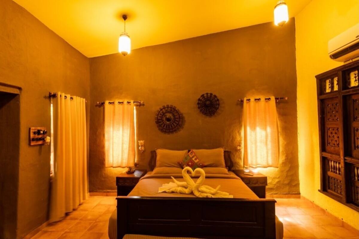 A bedroom with a bed, two bedside tables, curtains, wall decor, and a wooden cabinet.
