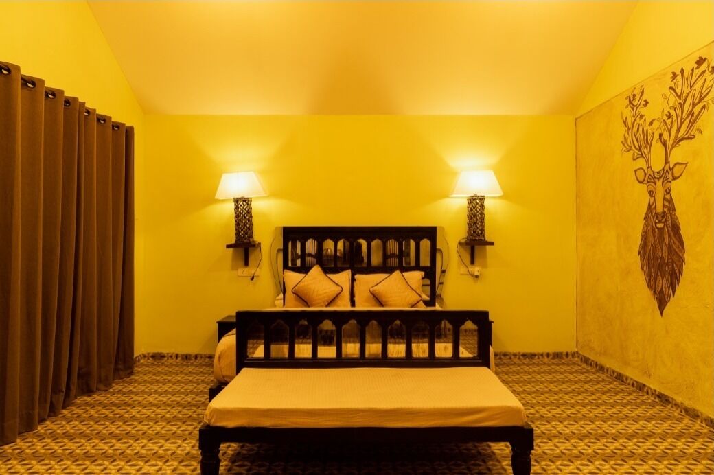 A room with a bed, two wall-mounted lamps, a patterned carpet, and a wall painting.