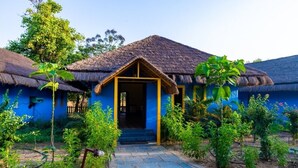 Una casa tradicional con techo de paja, fachada azul y puerta principal de madera.